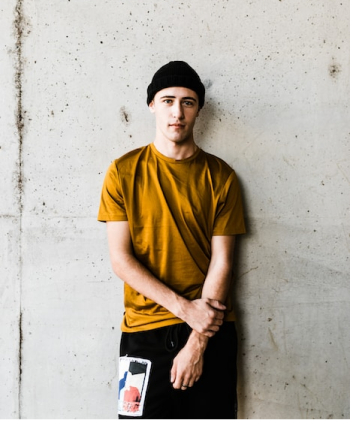Homem vestindo camiseta mostarta de touca e calça preta